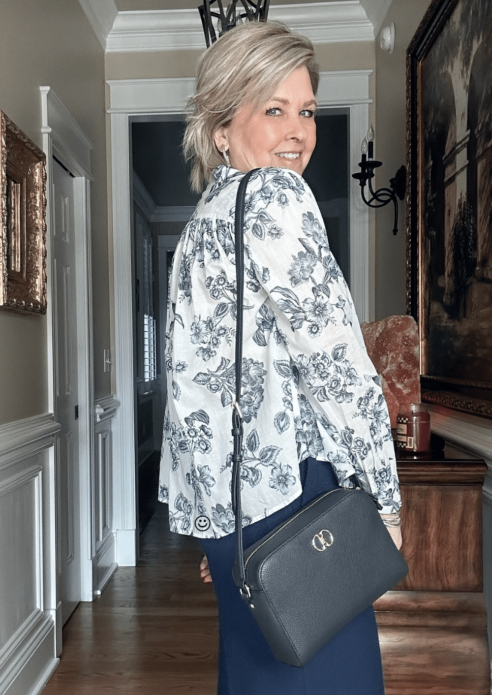 Over 50 fashion blogger, Tania Stephens is wearing a blue floral top with a navy crossbody